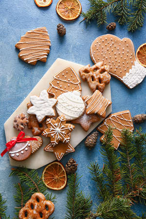 Composition with tasty gingerbread cookies and fir branches on color background