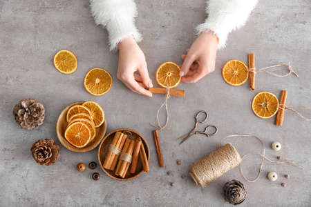 Woman making handmade Christmas toys on gray backgroundの写真素材