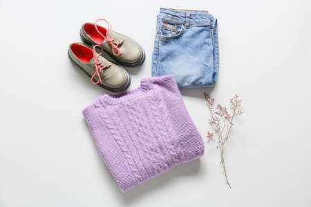 Set of stylish children's clothes and flower branch on white backgroundの写真素材