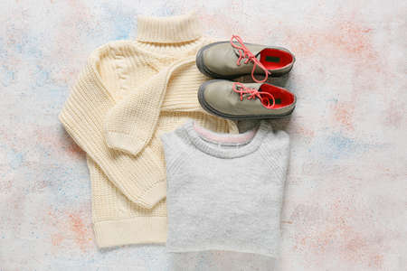 Warm children's sweaters and shoes on light backgroundの写真素材