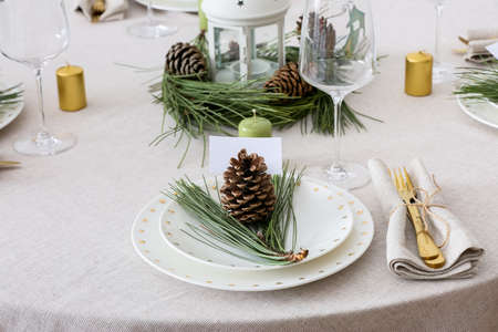 Beautiful table setting with pine cones, blank card and fir branchesの写真素材