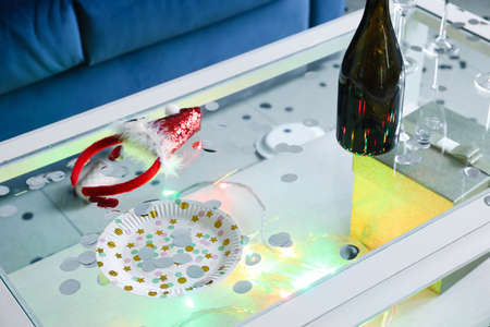Table with decor and empty champagne bottle in room after Christmas partyの写真素材