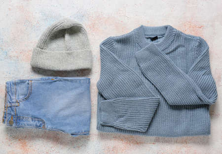 Knitted sweater, jeans and hat on light background