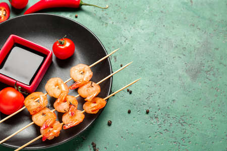Plate with grilled shrimp skewers and sauce on green backgroundの写真素材