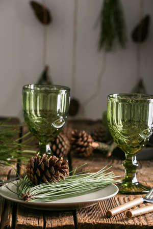 Beautiful table setting with pine cones and fir branches indoorsの写真素材