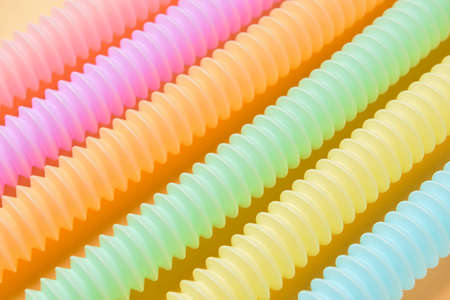 Different colorful Pop Tubes on color background, closeup