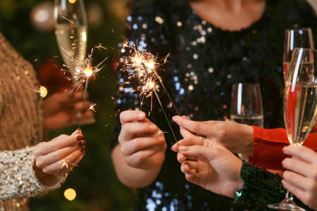 Beautiful young women with sparklers and glasses of champagne celebrating Christmasの写真素材