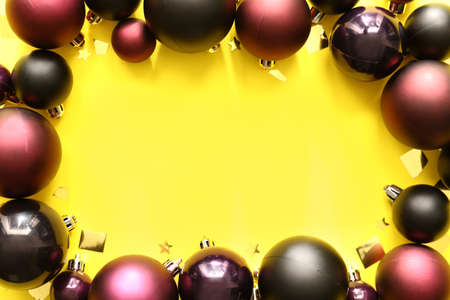 Frame made of different Christmas balls on yellow background, closeup