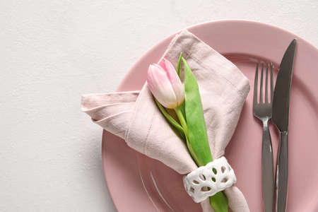 Stylish table setting with tulip flower on light background