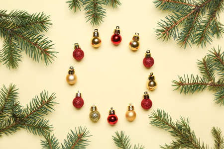 Frame made of different Christmas balls and fir branches on color background