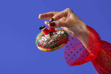 Woman holding tasty Christmas donut on blue background