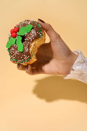 Woman holding bitten Christmas donut on beige backgroundの写真素材