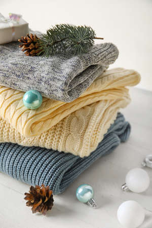Stylish baby sweaters and Christmas decor on light background, closeup