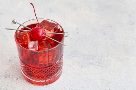Glass of iced Manhattan cocktail on light background, closeup