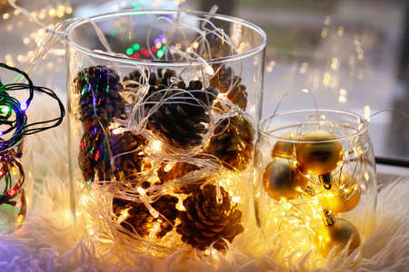 Jars with Christmas decor and glowing lights on fluffy fabric surface