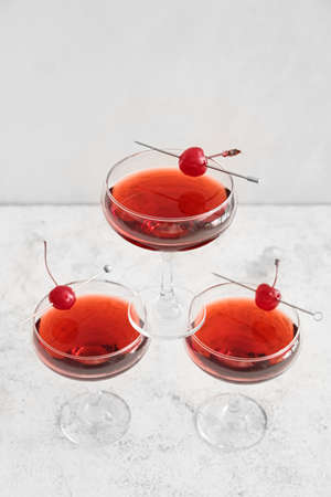 Glasses of tasty Manhattan cocktail with cherries on white backgroundの写真素材