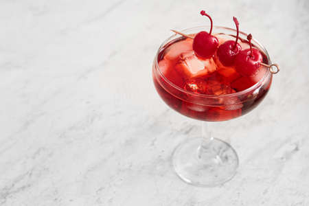 Glass of iced Manhattan cocktail with cherries on light background, closeupの写真素材