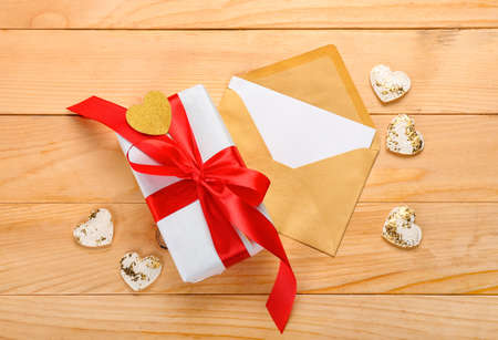 Envelope with blank card and gift for Valentine's Day on wooden background