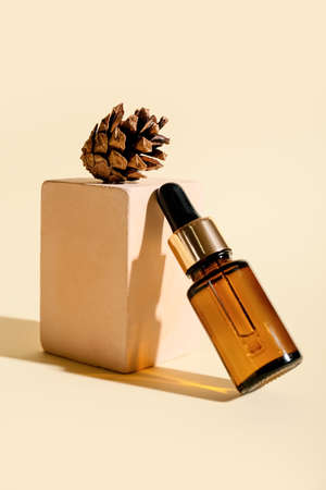 Composition with bottle of essential oil and cone on color backgroundの写真素材