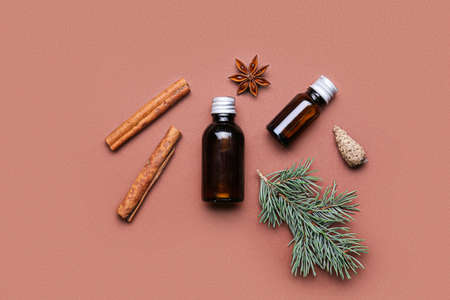Composition with bottles of essential oil, spices, fir branch and cone on color backgroundの写真素材