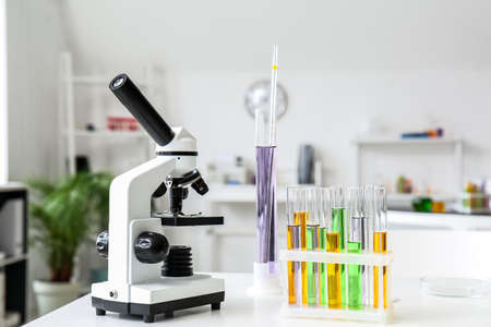 Modern microscope and test tubes on table in medical laboratory
