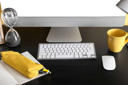 Modern computer, notebook, pencil case and cup on dark table