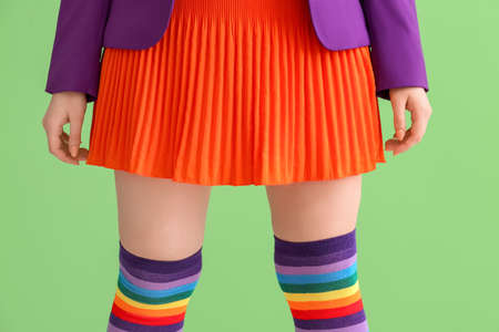 Young woman in rainbow stockings on green background. LGBT concept