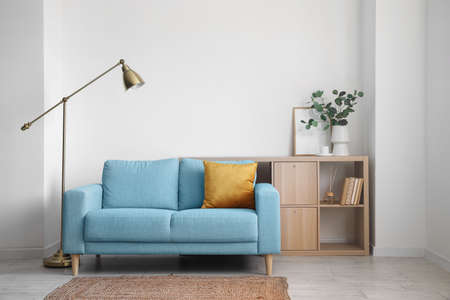 Interior of light living room with blue sofa, lamp and shelving unitの写真素材