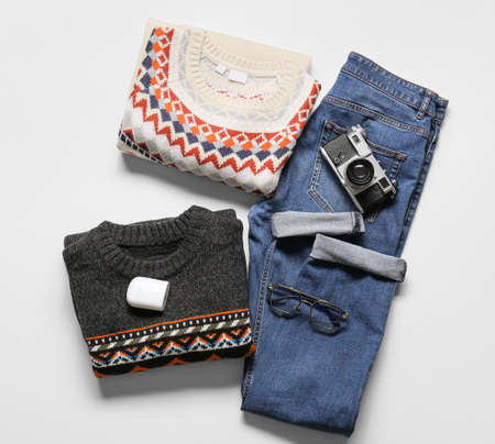 Male sweaters, jeans, earphones, photo camera and eyeglasses on light background