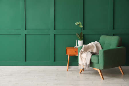 Table and armchair near green wall in roomの写真素材