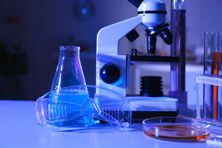 Test tube, conical flask and safety goggles on table in medical laboratory