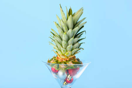 Composition with Christmas balls and leaves of pineapple on blue background, closeup