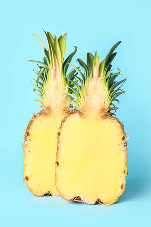 Halves of fresh juicy pineapple on color background