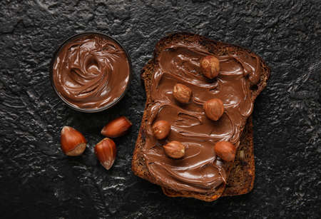 Bread with chocolate paste and hazelnuts on black backgroundの写真素材