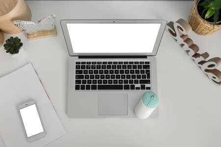 Modern laptop, computer mouse and mobile phone on light tableの写真素材
