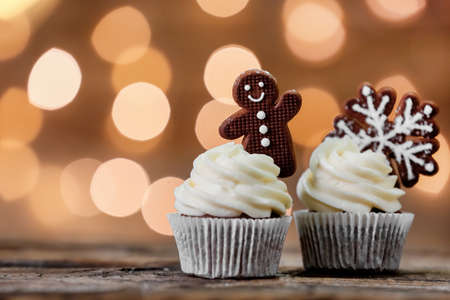 Tasty Christmas cupcakes with gingerbread cookies on table against blurred backgroundの写真素材