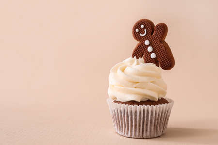 Tasty Christmas cupcake with gingerbread cookie on beige backgroundの写真素材