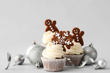 Tasty Christmas cupcakes with gingerbread cookies and decor on light backgroundの写真素材