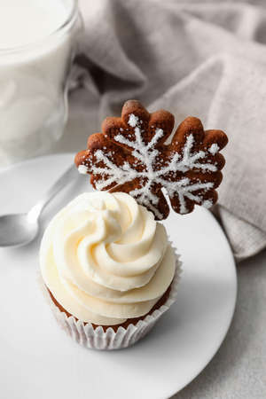 Plate of tasty Christmas cupcake with gingerbread cookie on light backgroundの写真素材