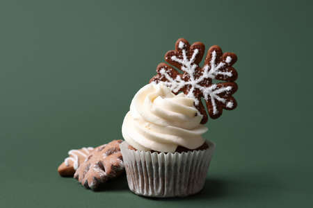 Tasty Christmas cupcake with gingerbread cookies on green backgroundの写真素材