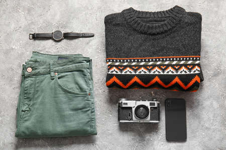 Male sweater, pants, wristwatch, photo camera and mobile phone on grunge backgroundの写真素材