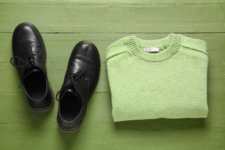 Warm male sweater and shoes on green wooden backgroundの写真素材