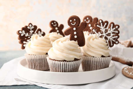 Tray of tasty Christmas cupcakes with gingerbread cookies on tableの写真素材