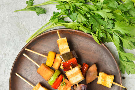 Plate with grilled tofu cheese skewers and parsley on light backgroundの写真素材