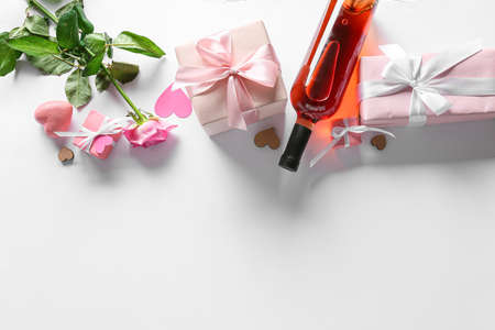 Gifts for Valentine's Day, bottle of wine and rose on light backgroundの写真素材