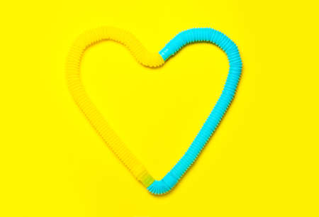 Heart made of Pop Tubes on yellow backgroundの写真素材