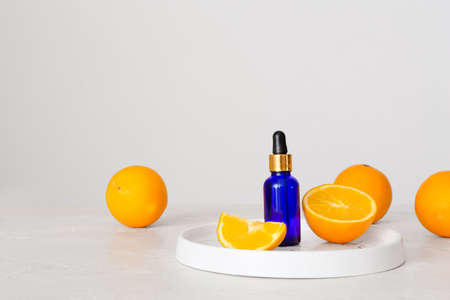 Bottle of essential oil and fresh orange on light backgroundの写真素材
