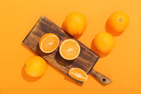 Board with fresh oranges on color backgroundの写真素材