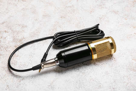 Modern microphone with wire on light background