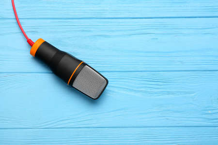 New modern microphone on color wooden background